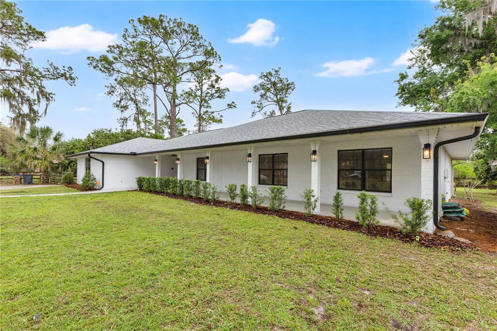 A white brick ranch-style house features a covered front porch and black window frames — 1985 MUSTANG COURT, ST CLOUD, FL