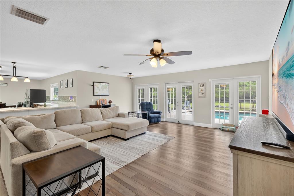 A spacious living room features a large sectional sofa, wood flooring, and glass patio doors — 1985 MUSTANG COURT, ST CLOUD, FL