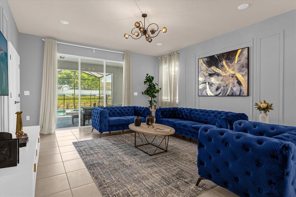 A living room features blue tufted sofas, a patterned area rug, and sliding glass doors — 3937 LANA AVENUE, DAVENPORT, FL