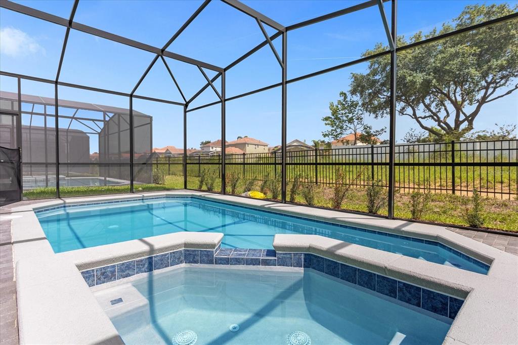 A swimming pool and attached hot tub are enclosed within a screened-in lanai — 3937 LANA AVENUE, DAVENPORT, FL