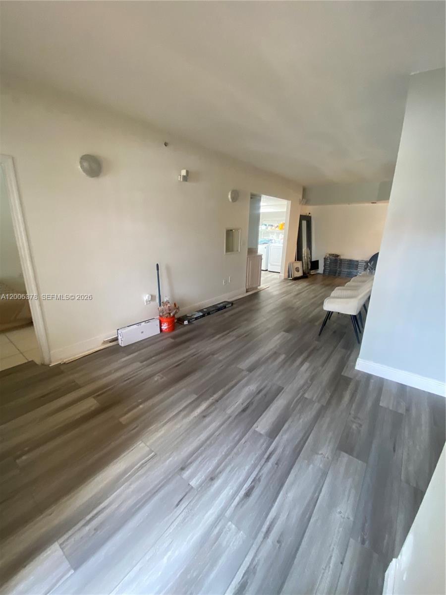An empty room features light gray wood-look flooring and white walls — 17405 NW 75th Pl # 107, Hialeah FL 33015, HIALEAH, FL