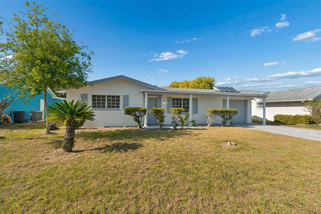 A single-story house with a white exterior, a front porch, and a grassy yard — 3667 ROCKAWAY DRIVE, HOLIDAY, FL