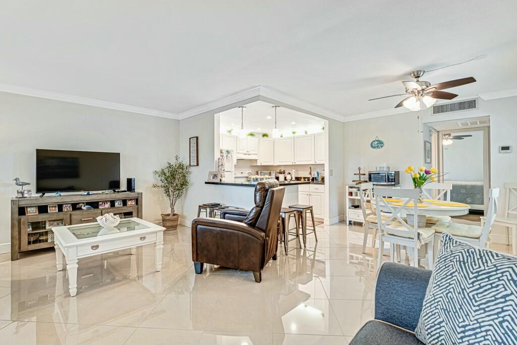 A living room with tile floors, a television console, and an open kitchen with bar seating — 350 Tuscany G, Delray Beach FL 33446, DELRAY BEACH, FL