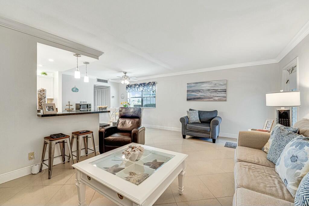 A living room with tile floors, a white coffee table, and a kitchen pass-through window — 350 Tuscany G, Delray Beach FL 33446, DELRAY BEACH, FL