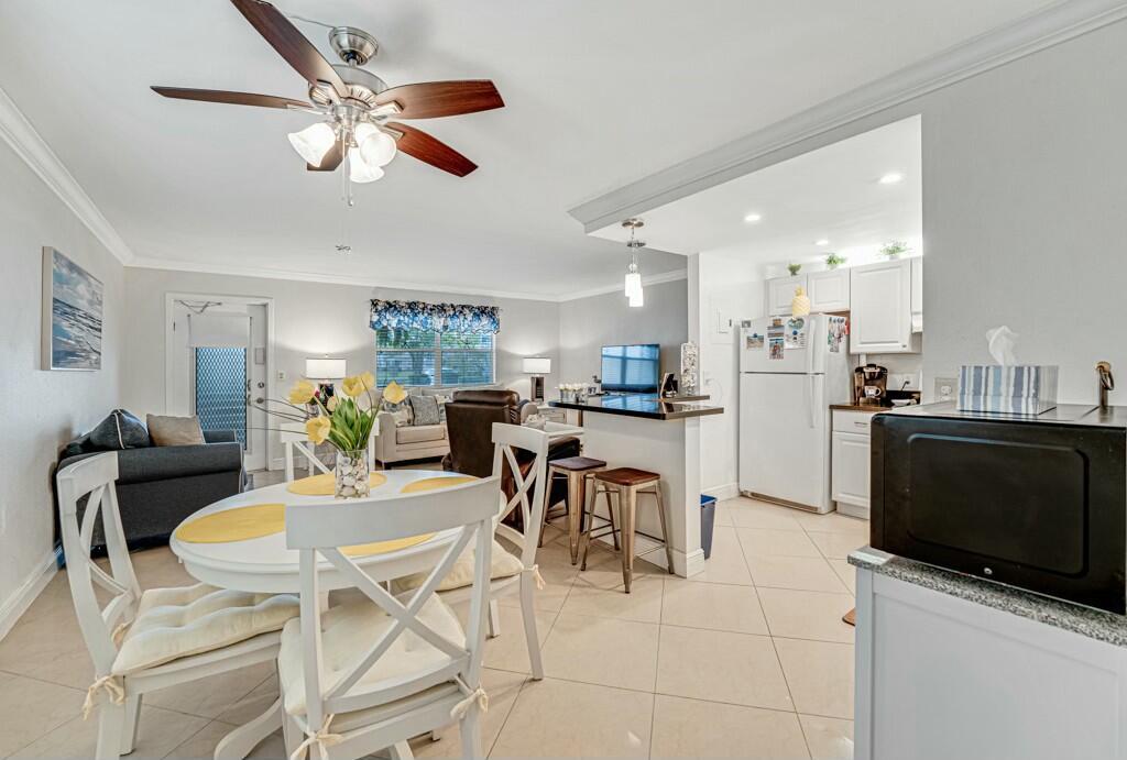 An open-concept living and dining area with a kitchen, tile floors, and a ceiling fan — 350 Tuscany G, Delray Beach FL 33446, DELRAY BEACH, FL