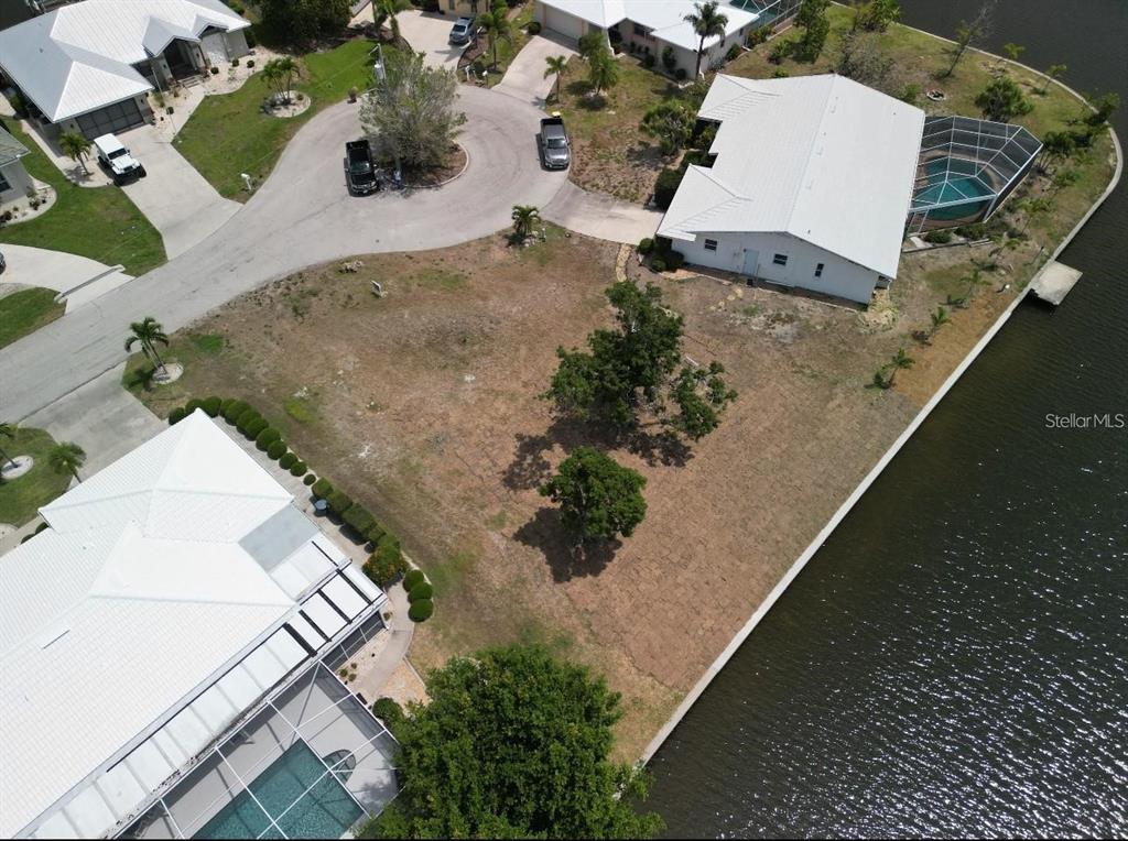 An aerial view shows a vacant waterfront lot situated between two houses with pools — 571 BELVEDERE COURT, PUNTA GORDA, FL