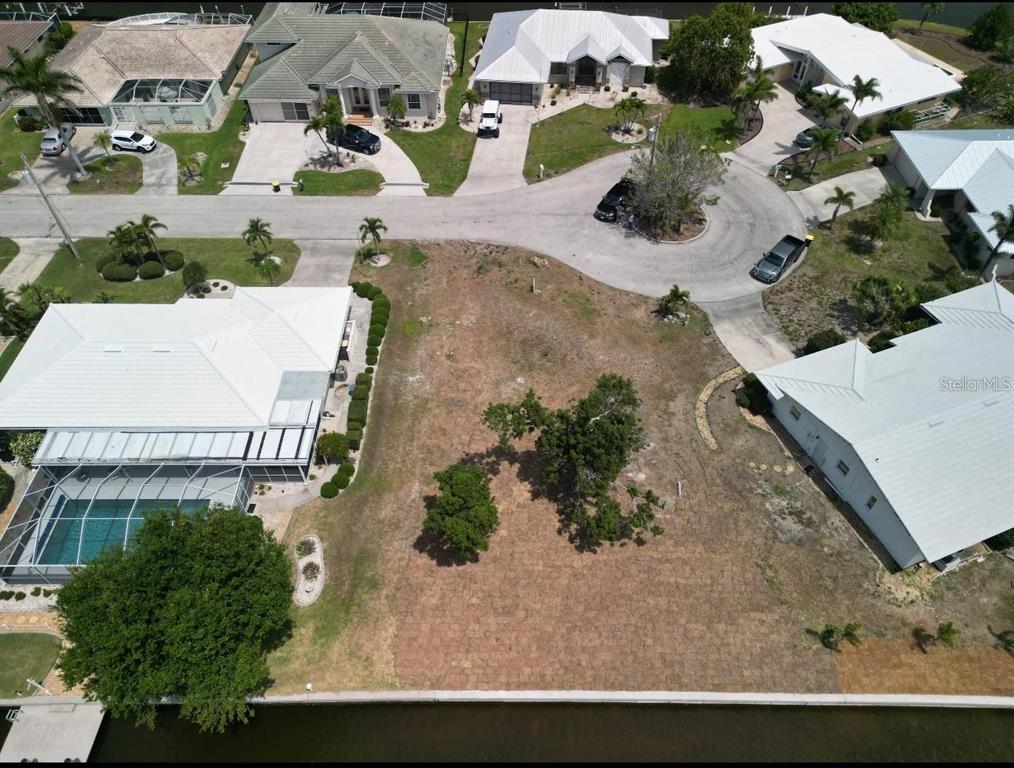 An aerial view shows a vacant residential lot situated between two houses along a canal — 571 BELVEDERE COURT, PUNTA GORDA, FL