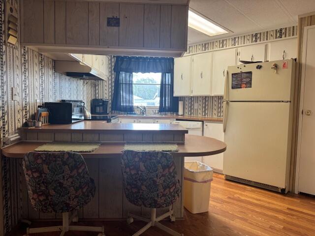 A kitchen features wood-paneled cabinetry, a breakfast bar with two chairs, and a white refrigerator — 1065 Echo Avenue, Moore Haven FL 33471, MOORE HAVEN, FL