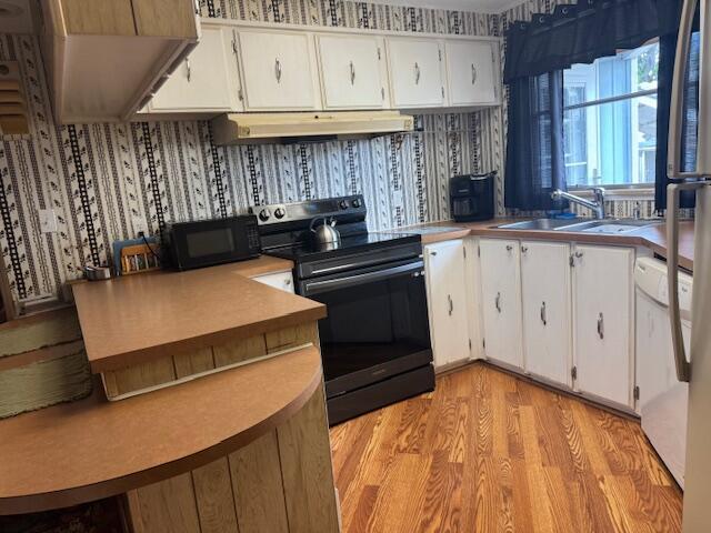 A kitchen features white cabinets, laminate countertops, black appliances, and patterned wallpaper — 1065 Echo Avenue, Moore Haven FL 33471, MOORE HAVEN, FL