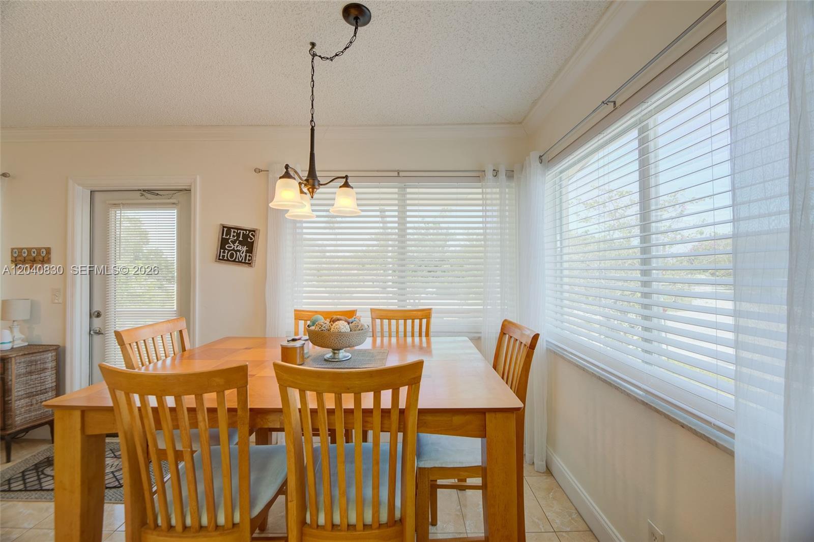 A dining room features a wooden table, six chairs, a hanging light fixture, and windows — 920 SW 10th Ter # 12R, Hallandale Beach FL 33009, HALLANDALE BEACH, FL