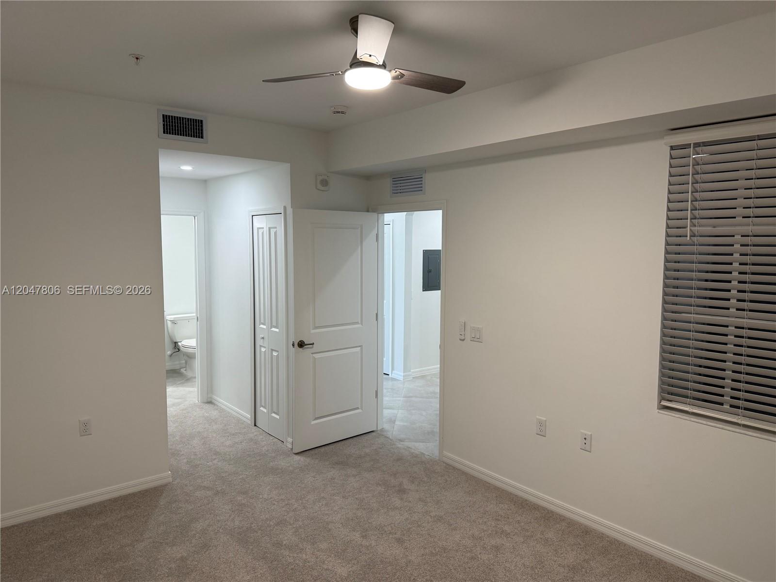 A carpeted bedroom features a ceiling fan, white walls, and two doorways leading to other rooms — 5491 Double Eagle Cir # 3732, Ave Maria FL 34142, AVE MARIA, FL