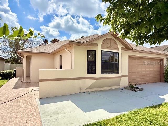 A single-story house with a beige stucco exterior, a tiled roof, and a two-car garage — 2911 WOOLRIDGE DRIVE, ORLANDO, FL