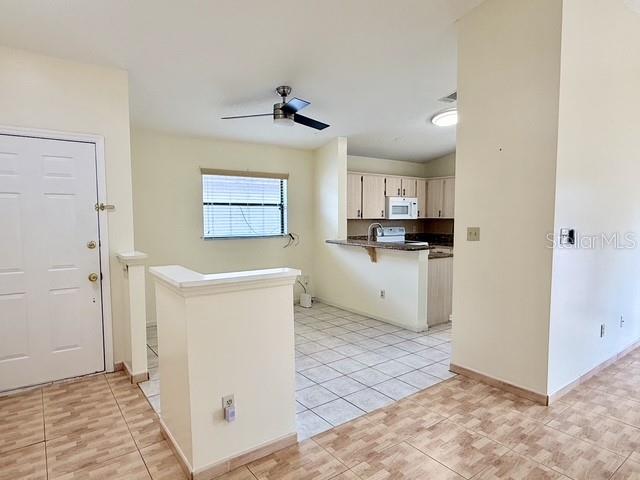 An open-concept kitchen and living area features tile flooring, light-colored walls, and a ceiling fan — 2911 WOOLRIDGE DRIVE, ORLANDO, FL