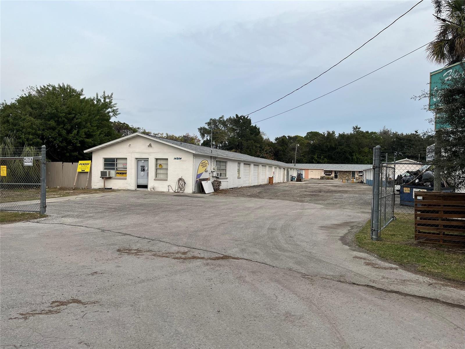 A white, single-story commercial building with storage units and a fenced parking lot — 14600 Marina Drive, FL 34667, FL