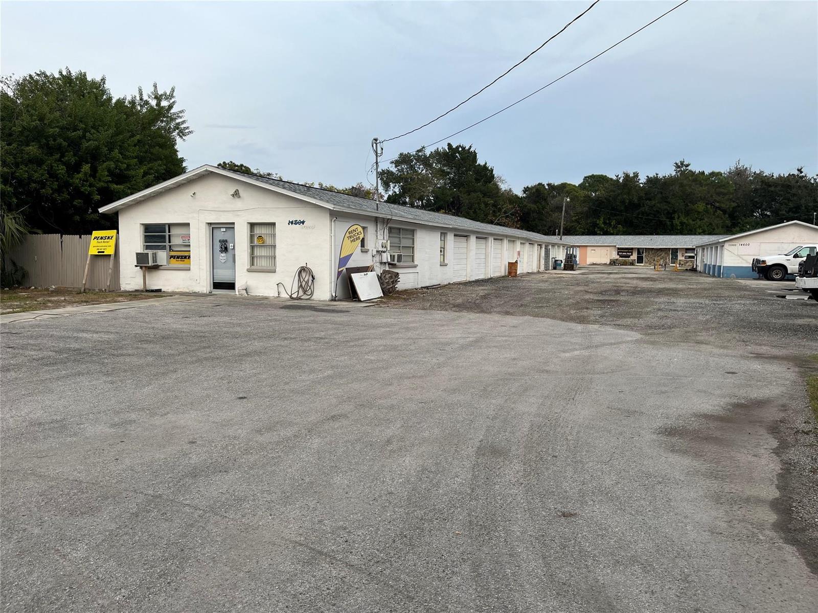 A white, single-story commercial building with multiple garage doors and a large gravel parking lot — 14600 Marina Drive, FL 34667, FL