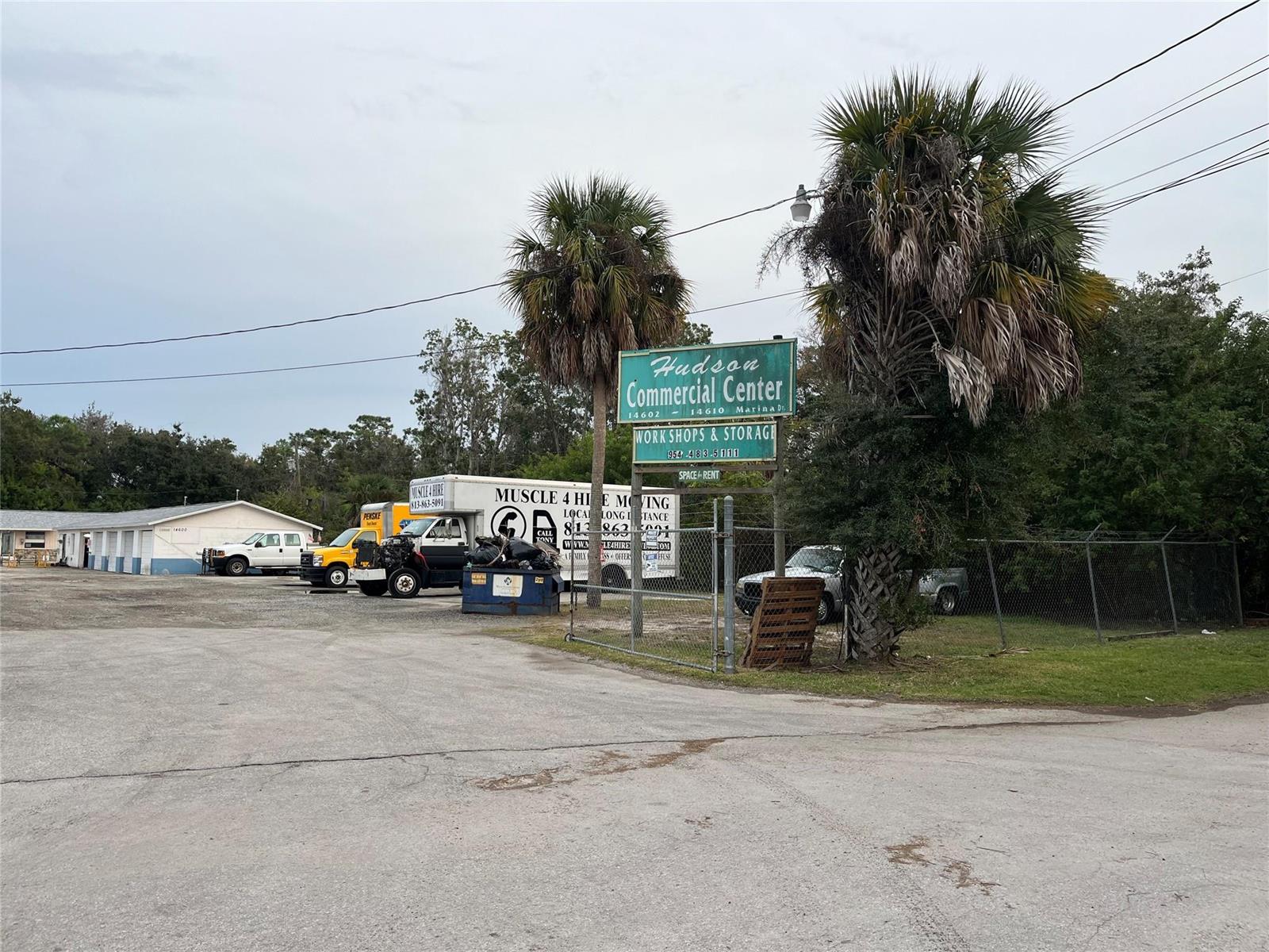 A commercial center sign stands in front of a parking lot with storage units and trucks — 14600 Marina Drive, FL 34667, FL