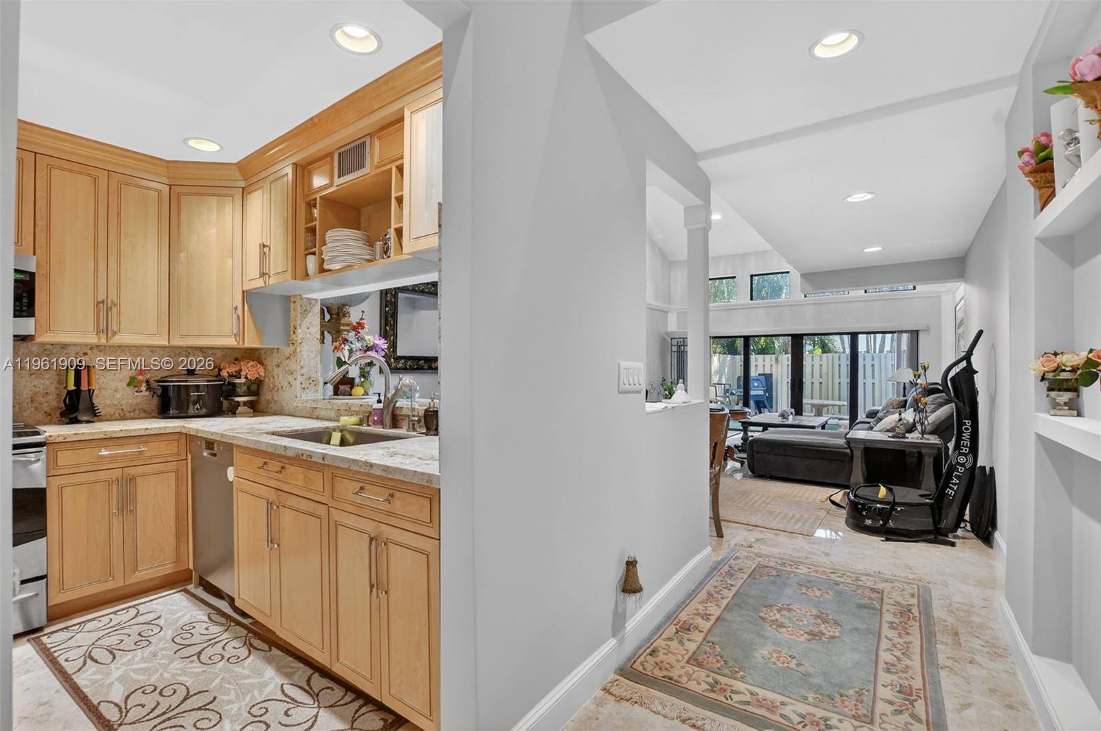 A kitchen with light wood cabinets and granite countertops opens into a living area — 1400 NW 9th Ave # 2, Boca Raton FL 33486, BOCA RATON, FL