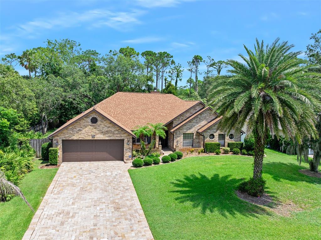 A stone-faced house with a brown roof, a paved driveway, and a large palm tree — 43 WINDING CREEK WAY, ORMOND BEACH, FL