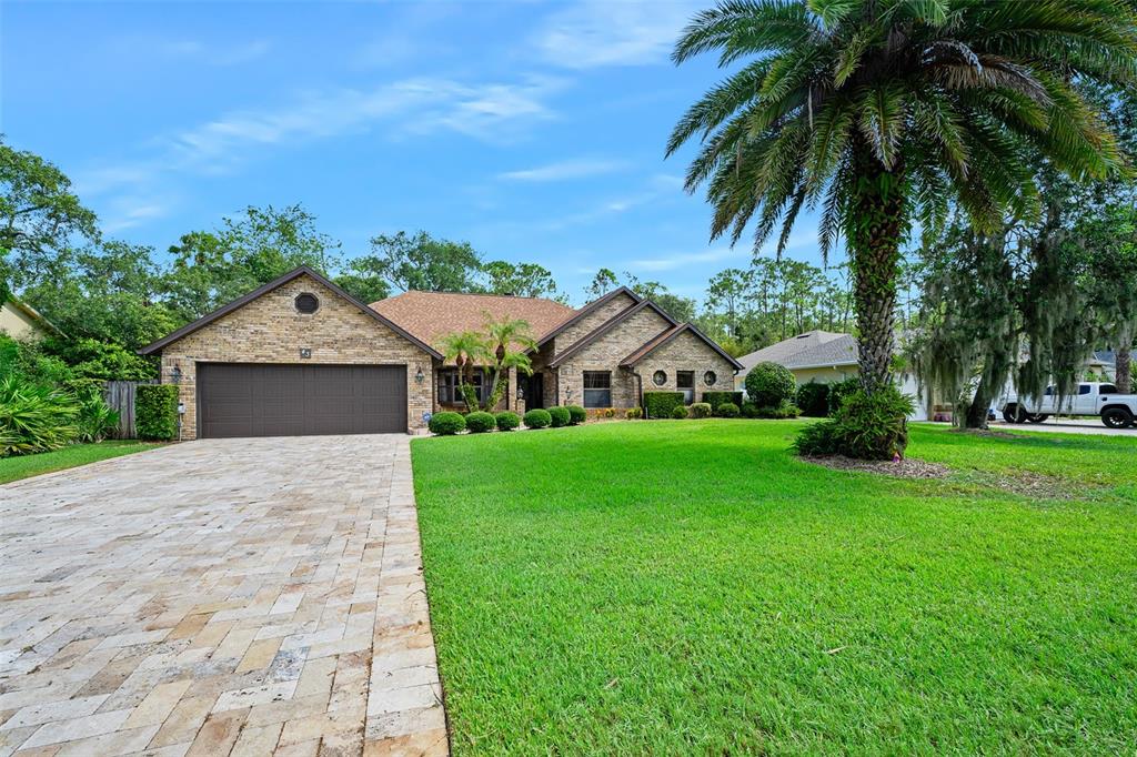 A single-story brick house with a paved driveway, a large lawn, and a palm tree — 43 WINDING CREEK WAY, ORMOND BEACH, FL
