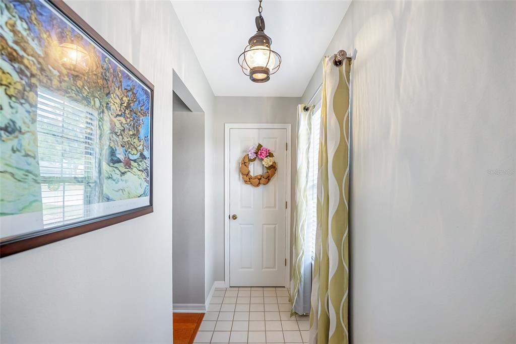 A tiled entryway features a white door with a wreath, a pendant light, and curtains — 4535 NW 34TH PLACE, OCALA, FL