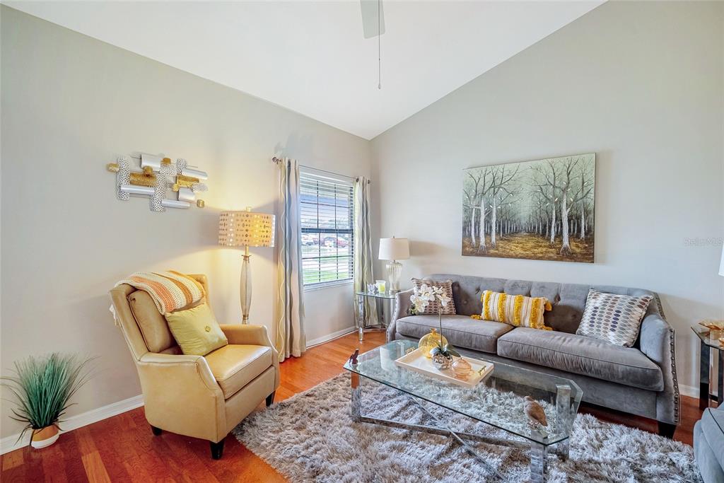 A living room features a gray sofa, a tan armchair, a glass coffee table, and hardwood floors — 4535 NW 34TH PLACE, OCALA, FL