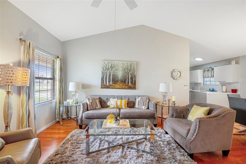 A living room features a gray sofa, an armchair, a glass coffee table, and hardwood floors — 4535 NW 34TH PLACE, OCALA, FL