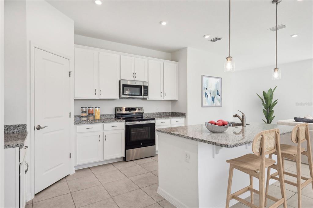A modern kitchen features white cabinets, granite countertops, stainless steel appliances, and a central island — 877 CASTLEFORD AVENUE NE, PALM BAY, FL
