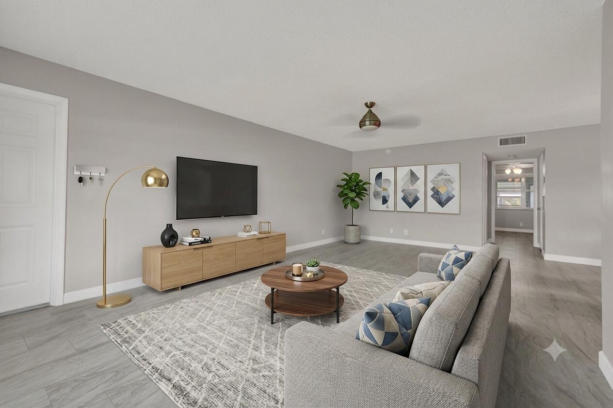 A living room features gray walls, wood-look tile flooring, a gray sofa, and a television — 185 High Point Terrace E # B, Delray Beach FL 33445, DELRAY BEACH, FL