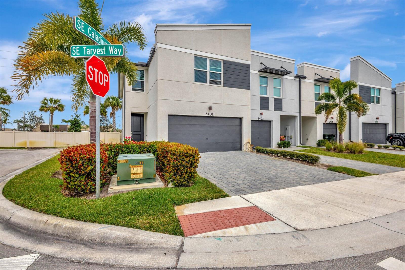 A modern multi-unit townhouse exterior with a paved driveway and a street sign corner — 2401 SE Tarvest Way, Stuart FL 34997, STUART, FL