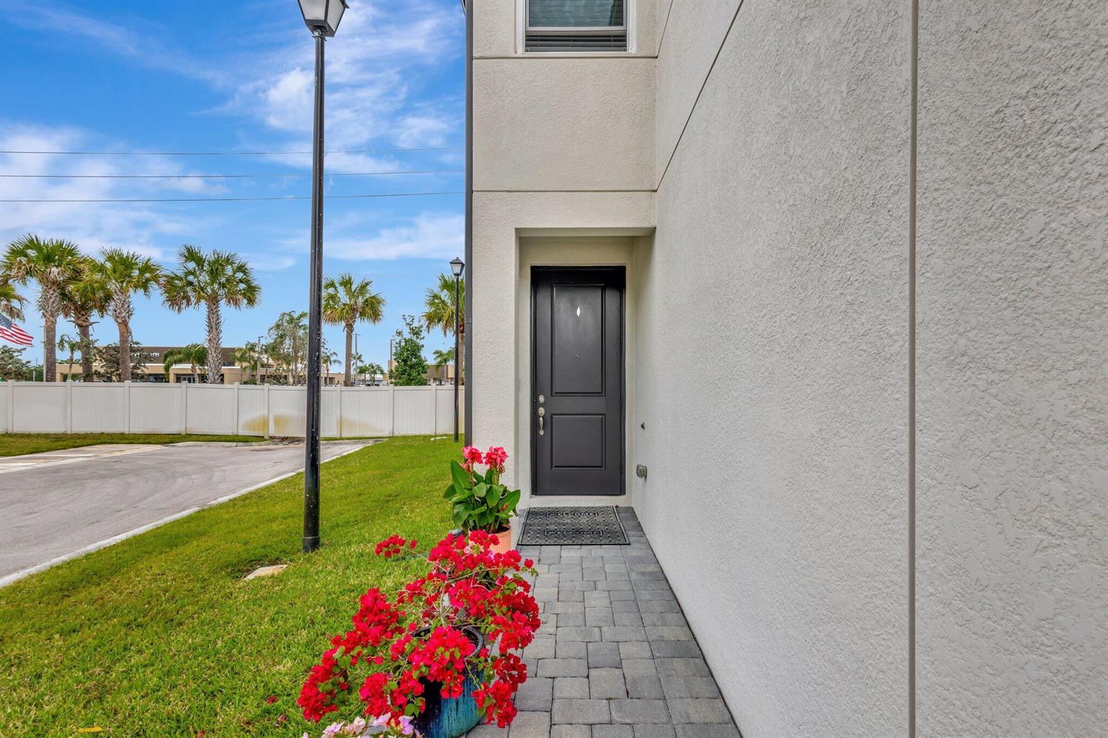 A paved walkway leads to a dark front door beside a patch of green grass — 2401 SE Tarvest Way, Stuart FL 34997, STUART, FL
