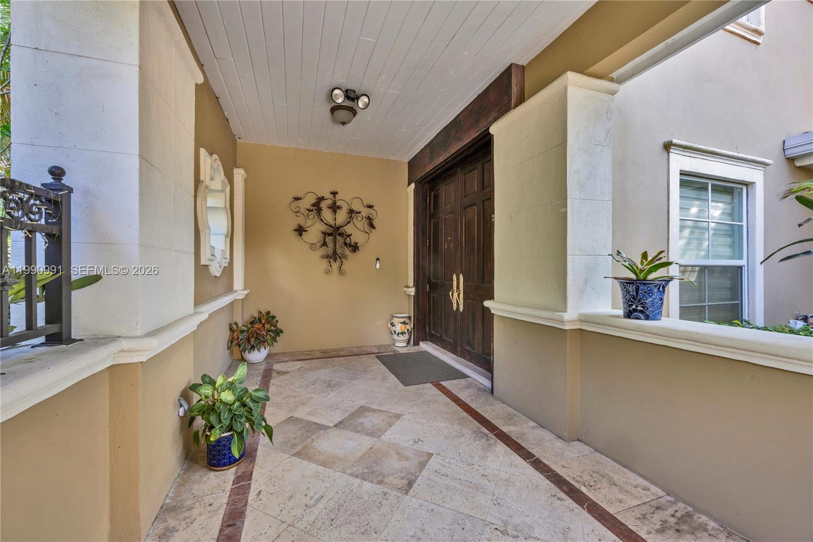 A covered entryway features a double wooden door, tiled flooring, and decorative wall accents — 6200 Granada Blvd, Coral Gables FL 33146, CORAL GABLES, FL