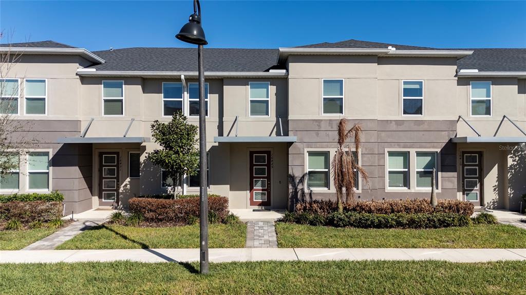 A row of modern two-story townhouses with gray stucco facades and dark-framed windows — 16425 PRAIRIE SCHOOL DRIVE, WINTER GARDEN, FL