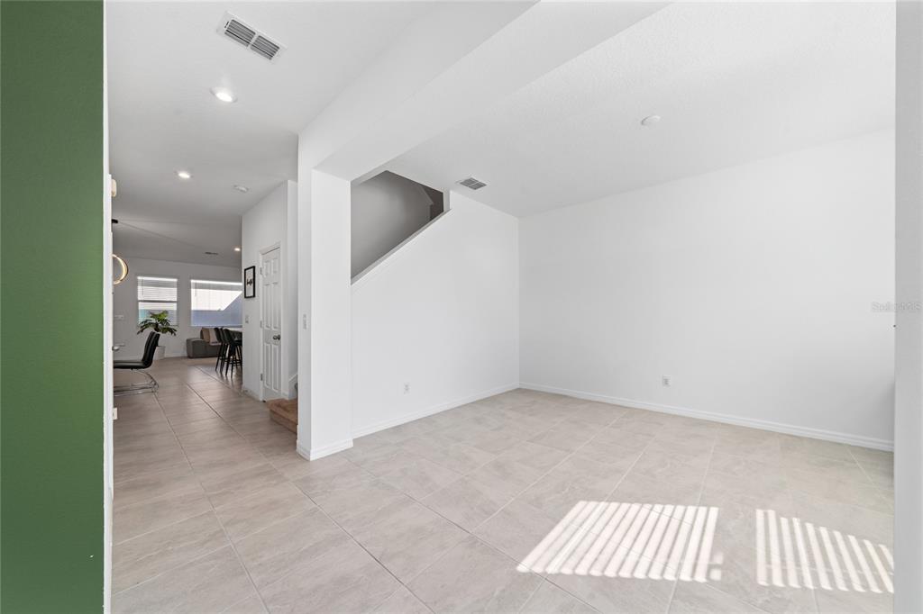A bright, open-concept living area features light tile flooring and a staircase leading upstairs — 16425 PRAIRIE SCHOOL DRIVE, WINTER GARDEN, FL