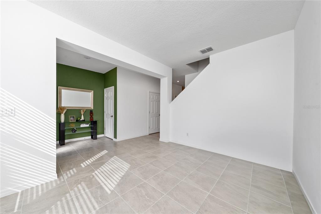 An interior view shows a tiled room with white walls, a green accent wall, and stairs — 16425 PRAIRIE SCHOOL DRIVE, WINTER GARDEN, FL