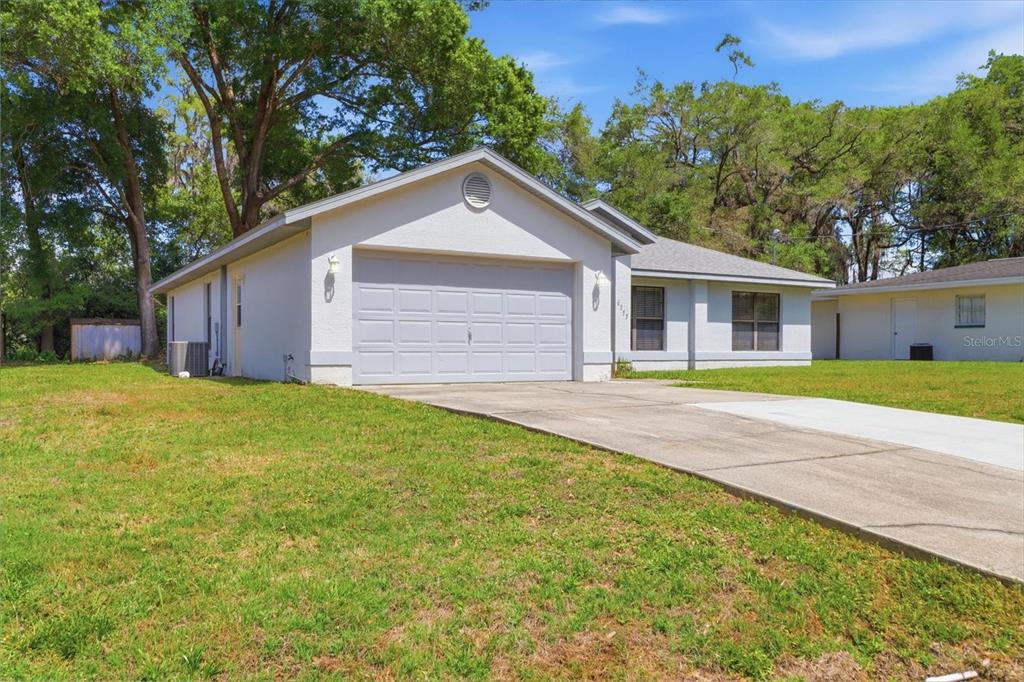 A single-story house with a light-colored stucco exterior, a two-car garage, and a concrete driveway — 6355 E RUSH STREET, INVERNESS, FL