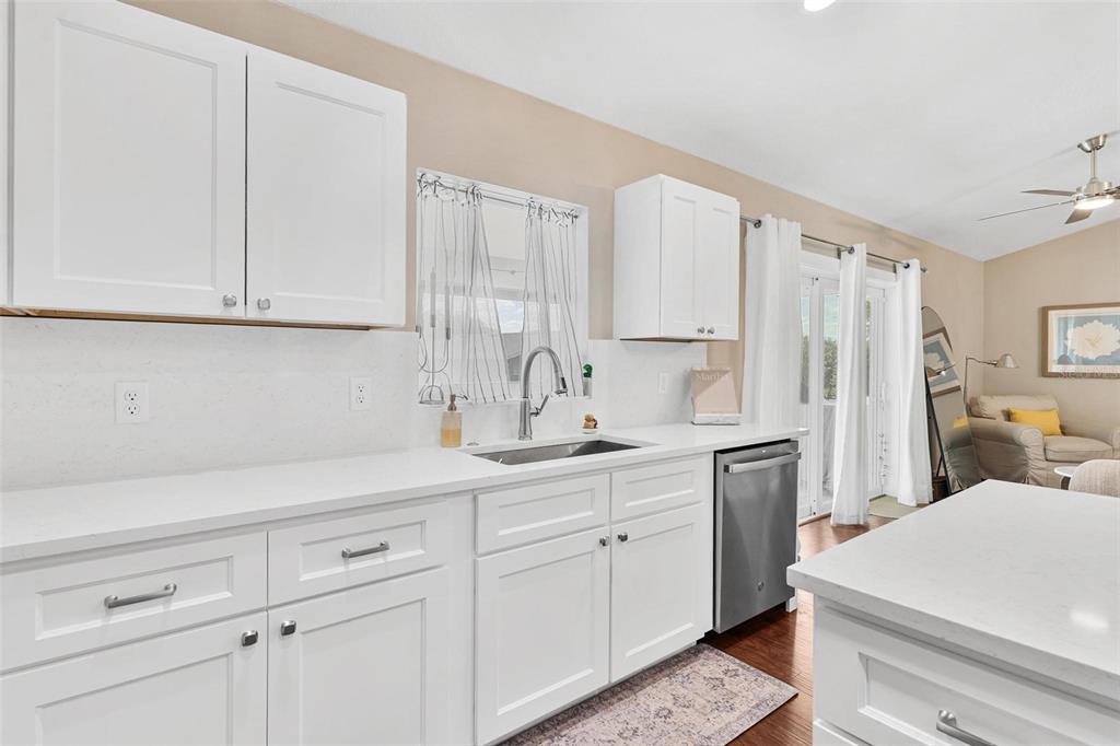 A kitchen features white cabinets, quartz countertops, a stainless steel dishwasher, and a sink — 206 SHANNON LANE, LADY LAKE, FL