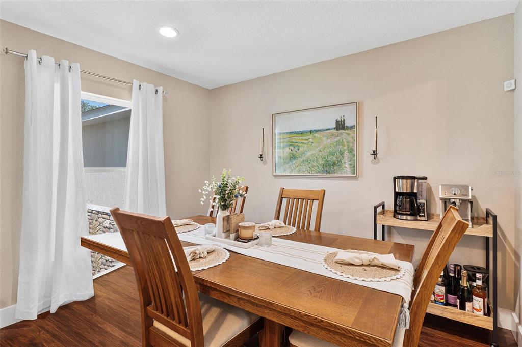 A dining room features a wooden table, chairs, a landscape painting, and a coffee station — 206 SHANNON LANE, LADY LAKE, FL