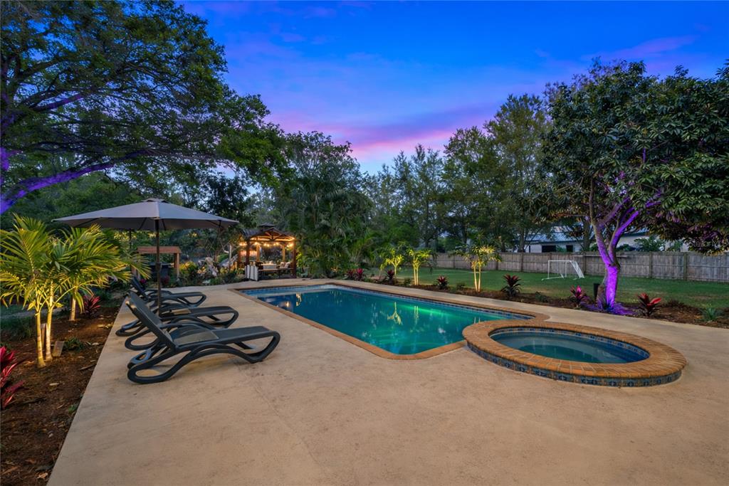 A backyard features a swimming pool, a circular spa, lounge chairs, and a wooden gazebo — 10852 131ST STREET N, LARGO, FL