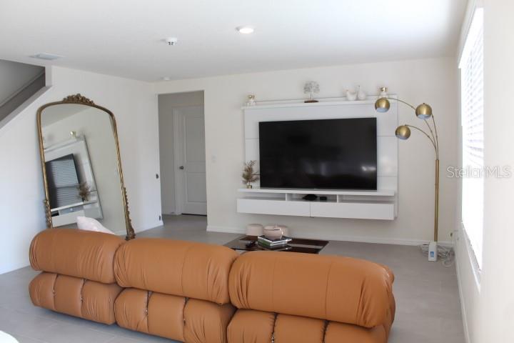 A living room features a tan leather sofa, a wall-mounted television, and a large floor mirror — 2182 NW 246TH TERRACE, NEWBERRY, FL