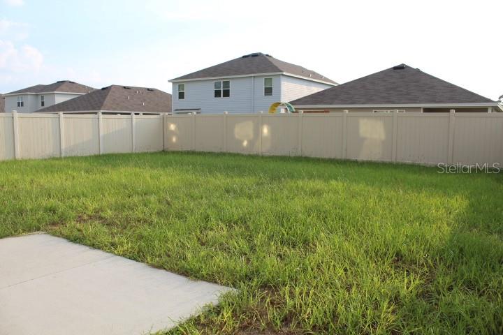 A backyard with a concrete patio and a tan vinyl privacy fence — 2182 NW 246TH TERRACE, NEWBERRY, FL