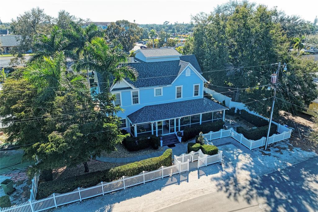 An aerial view of a two-story blue house with a wrap-around porch and white fencing — 1315 15TH AVENUE W, BRADENTON, FL