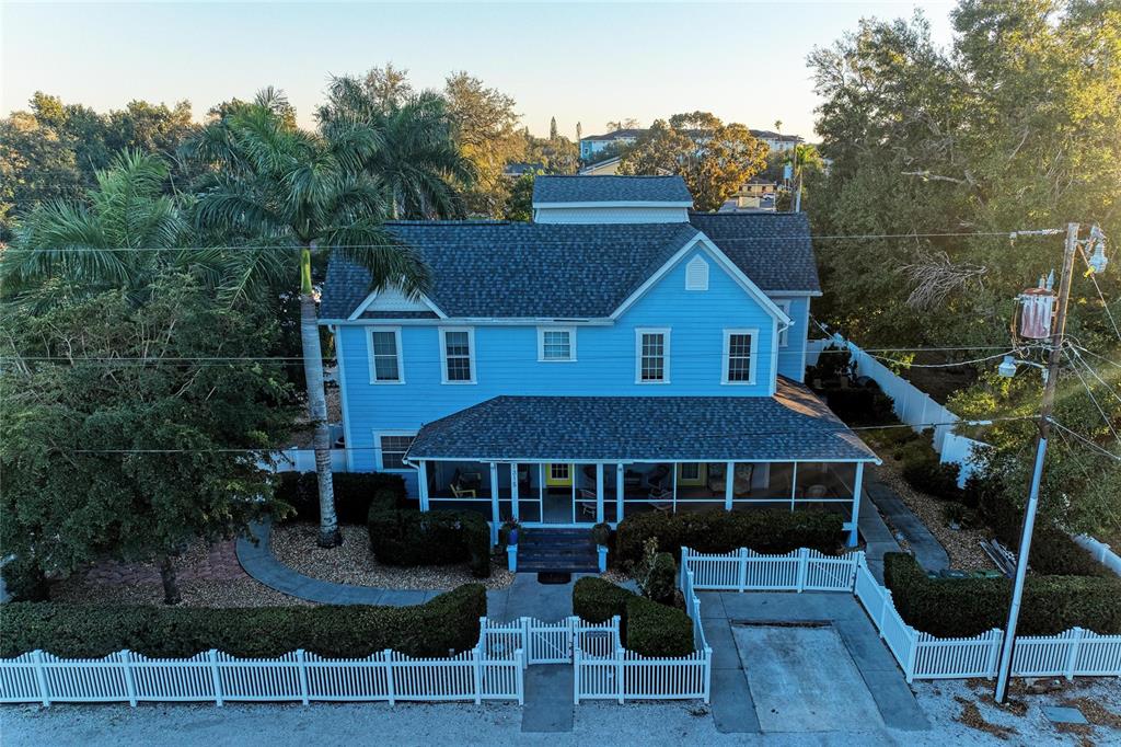 An aerial view of a two-story blue house with a screened front porch and fence — 1315 15TH AVENUE W, BRADENTON, FL
