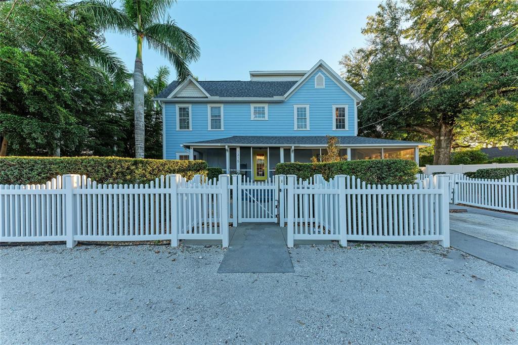 A two-story blue house with a white picket fence and a screened front porch — 1315 15TH AVENUE W, BRADENTON, FL