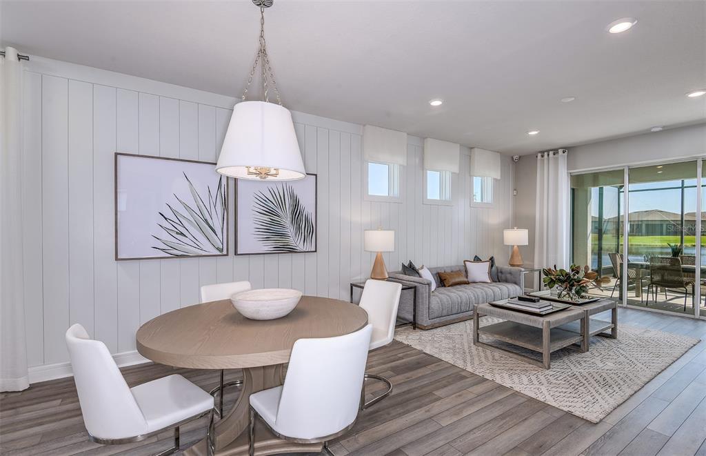 An open-concept dining and living area features wood-plank flooring, white vertical wall paneling, and furniture — 13780 ROCKY PINE PLACE, SPRING HILL, FL