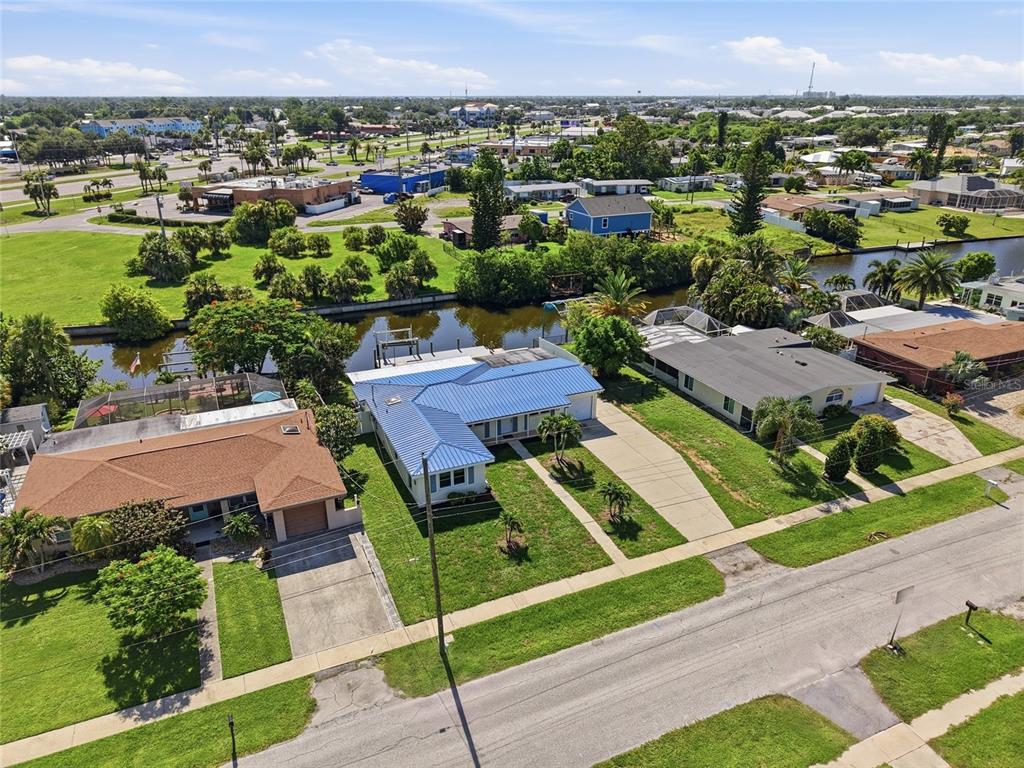 An aerial view shows three suburban houses with driveways and backyards bordering a narrow canal — 181 DUXBURY AVENUE, PORT CHARLOTTE, FL