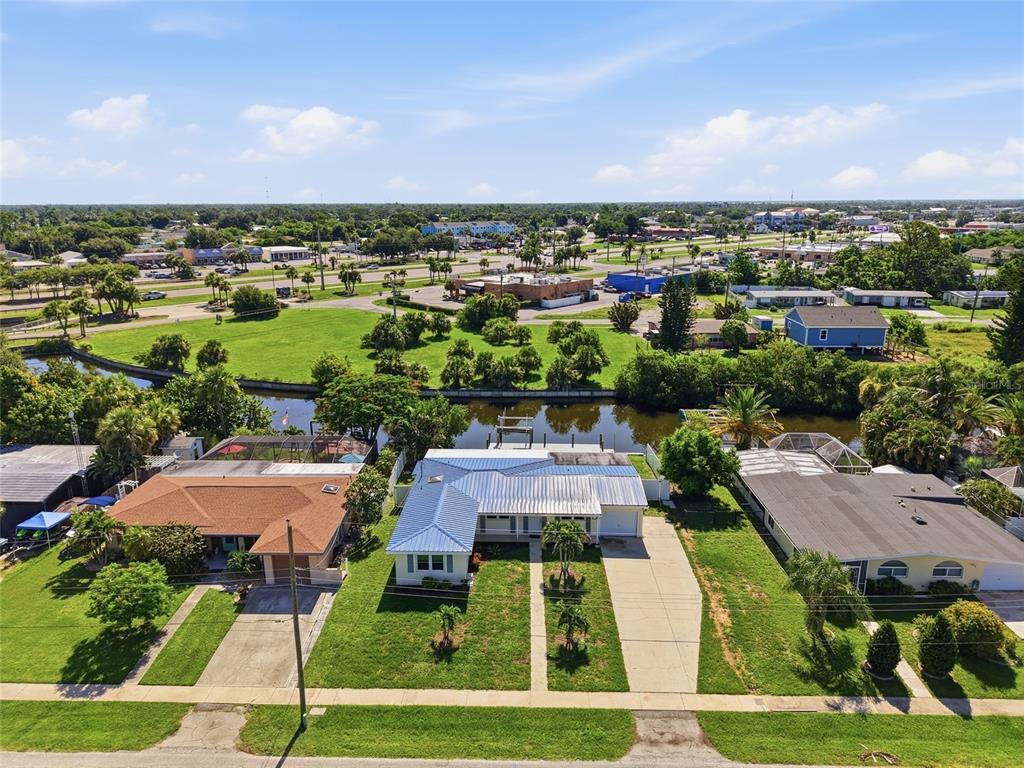 An aerial view shows a residential street with houses, a canal, and a grassy field — 181 DUXBURY AVENUE, PORT CHARLOTTE, FL