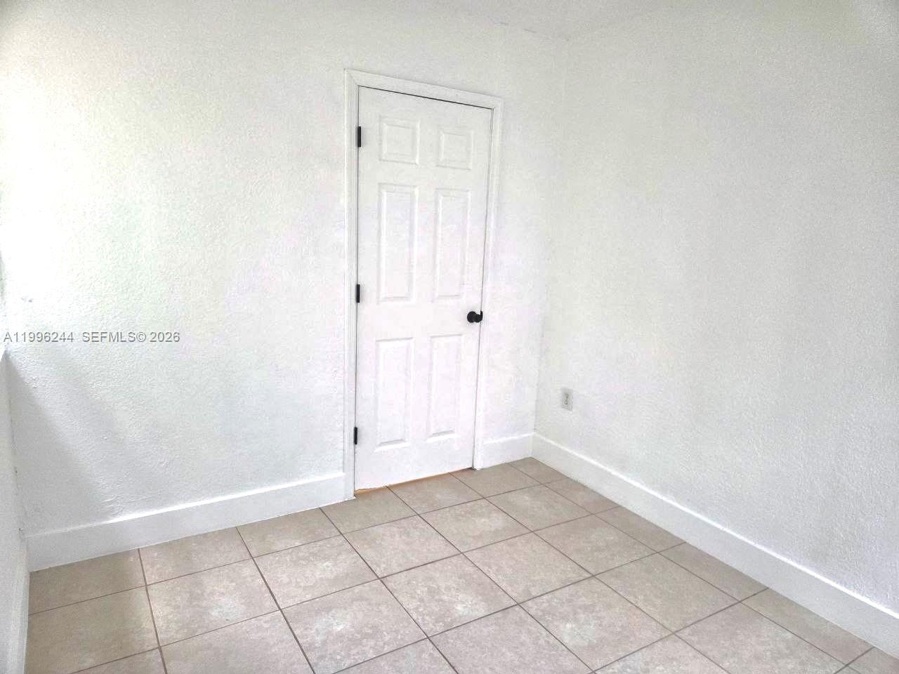 A small, empty room features white walls, a white door, and light-colored tile flooring — 34 SW 6th Ave # 4, Dania Beach FL 33004, DANIA BEACH, FL