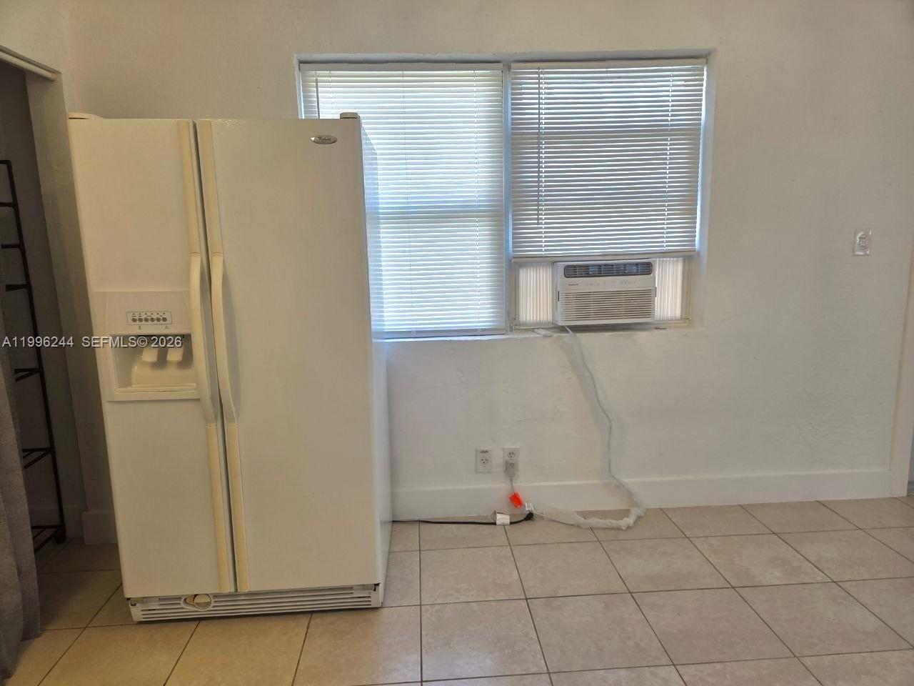 A white refrigerator stands next to a window with blinds and a wall-mounted air conditioner — 34 SW 6th Ave # 4, Dania Beach FL 33004, DANIA BEACH, FL