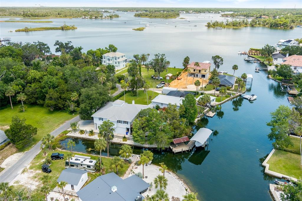 An aerial view shows waterfront homes with docks, a boat lift, and a construction site — 1035 N APPALACHIAN TERRACE, CRYSTAL RIVER, FL