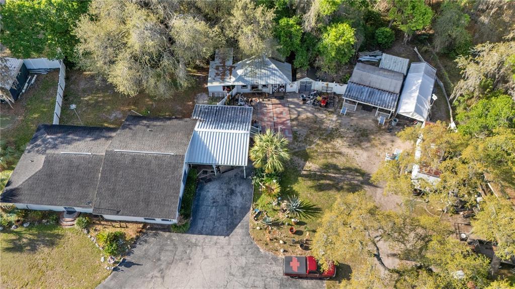 An aerial view shows a house with a metal carport, detached outbuildings, and a driveway — 270 W MCCLENDON STREET, LADY LAKE, FL